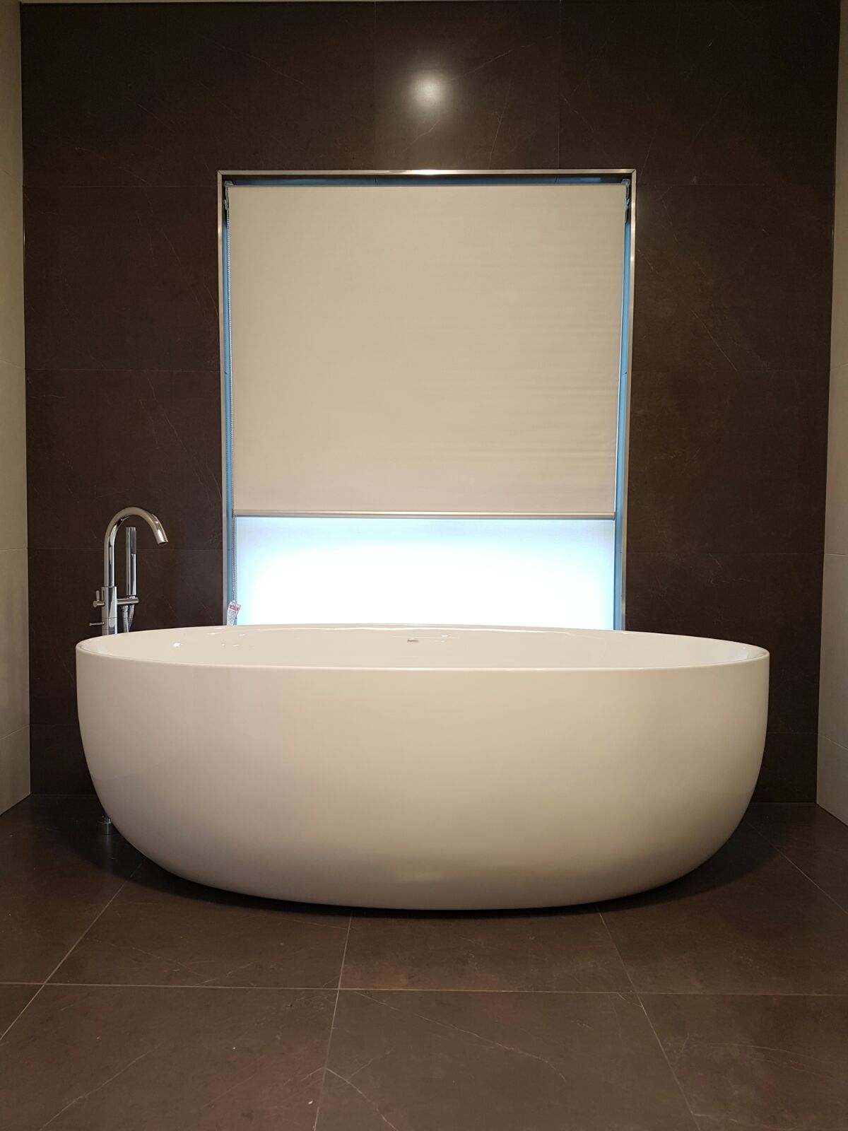 Double Roller blinds behind a large freestanding bathtub