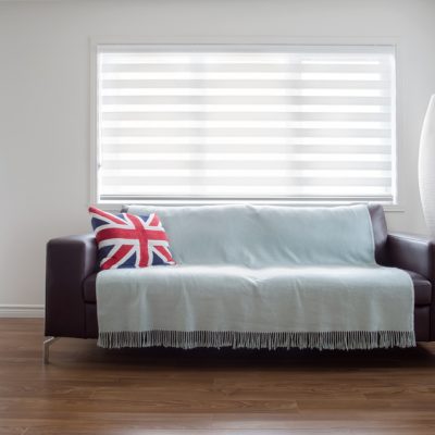 Horizontal image of  a modern leather sofa with throw and a Union Jack pillow, in bright living room. Space for copy.